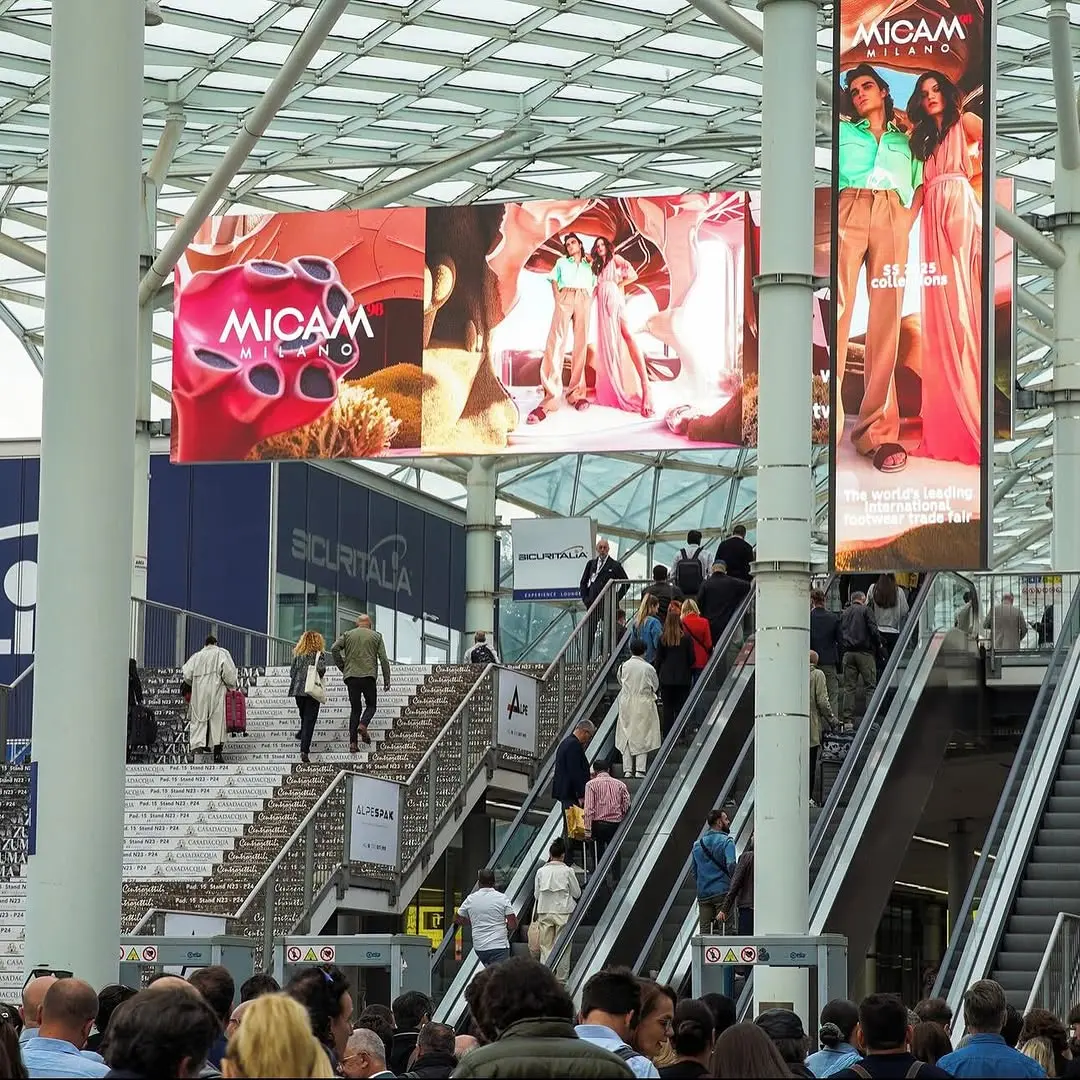 Foto cartellone e persone su scale mobili Micam Milano